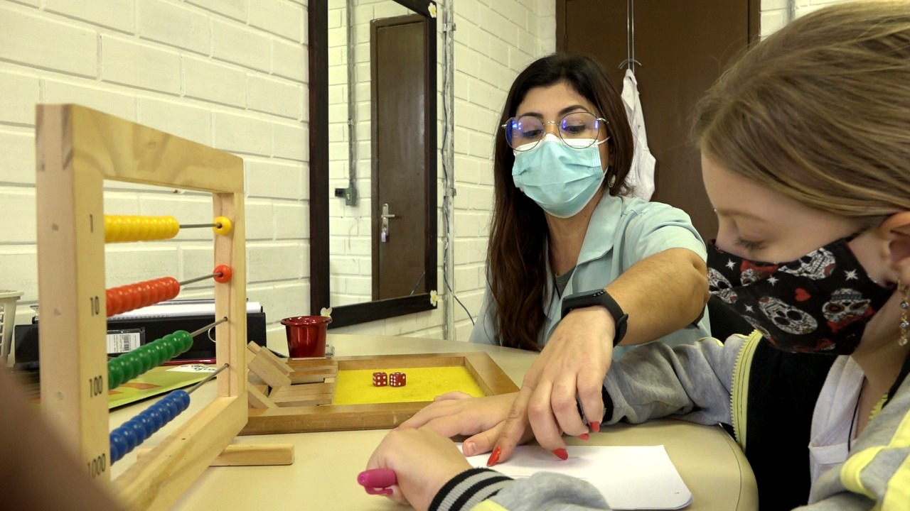 Uma mulher e uma criança, sala de aula, mesa de atividades