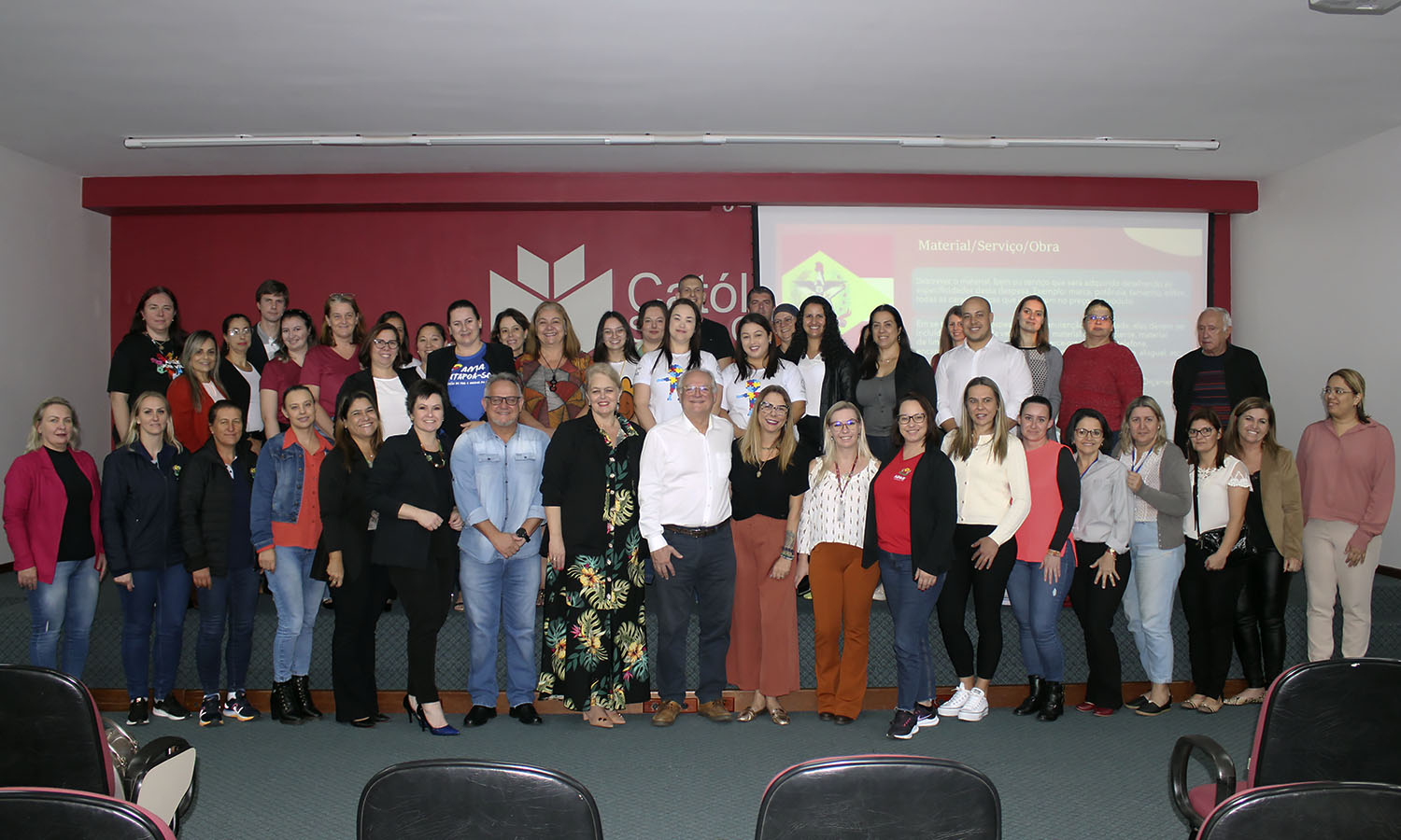 30 pessoas em pé posam para foto, ambiente interno