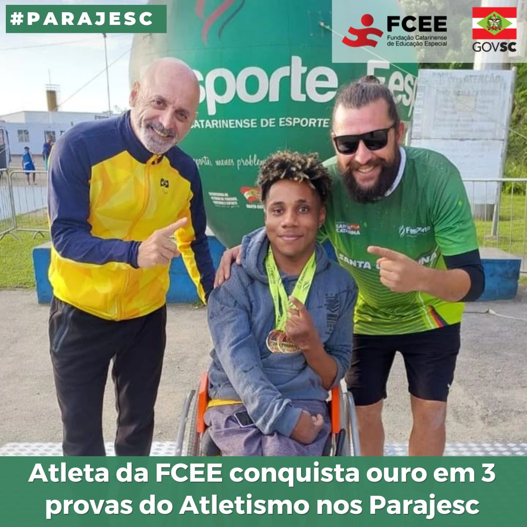 Três pessoas em pé segurando medalha, ambiente aberto.