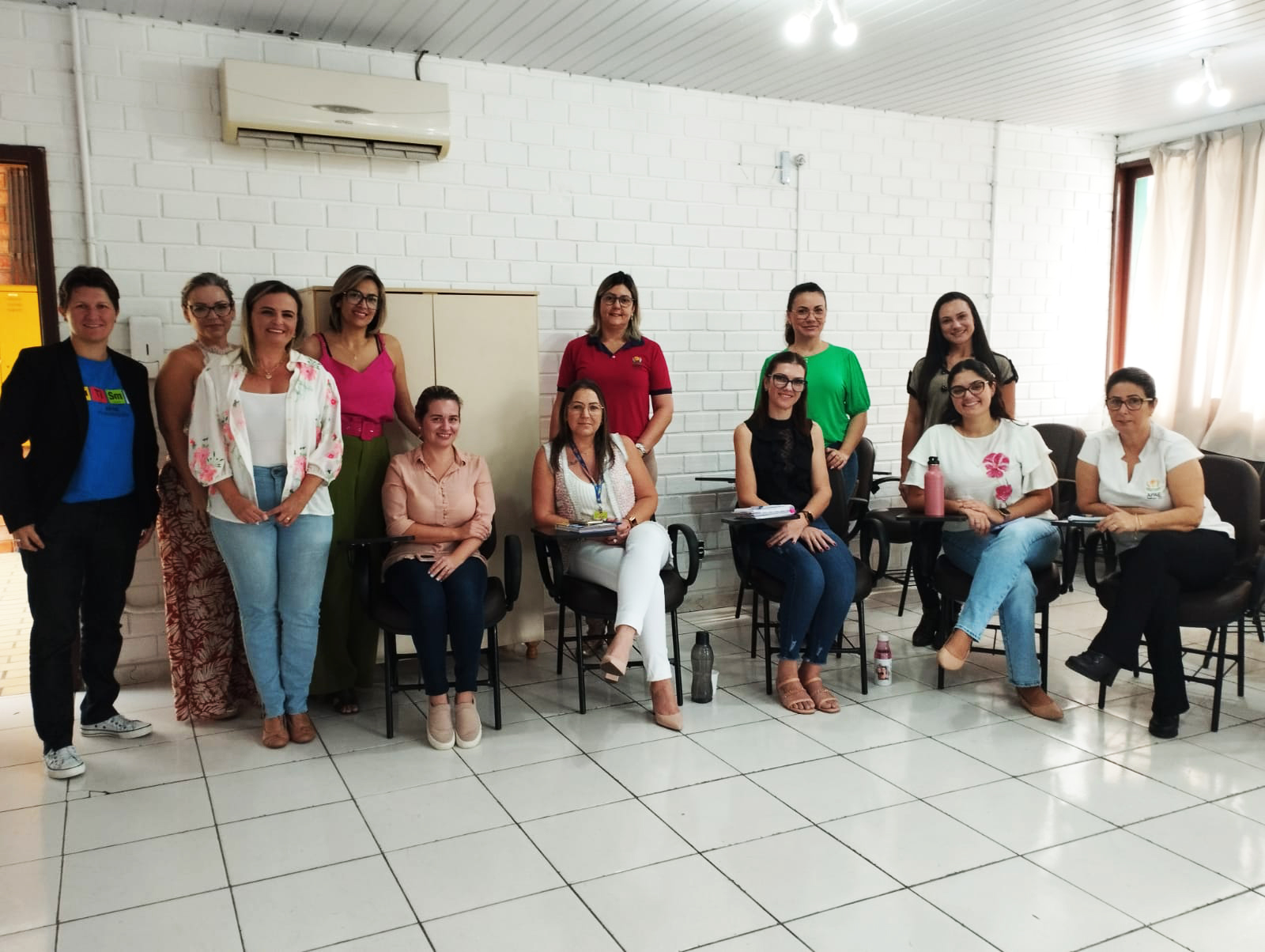 Doze pessoas posam para foto, sala de aula