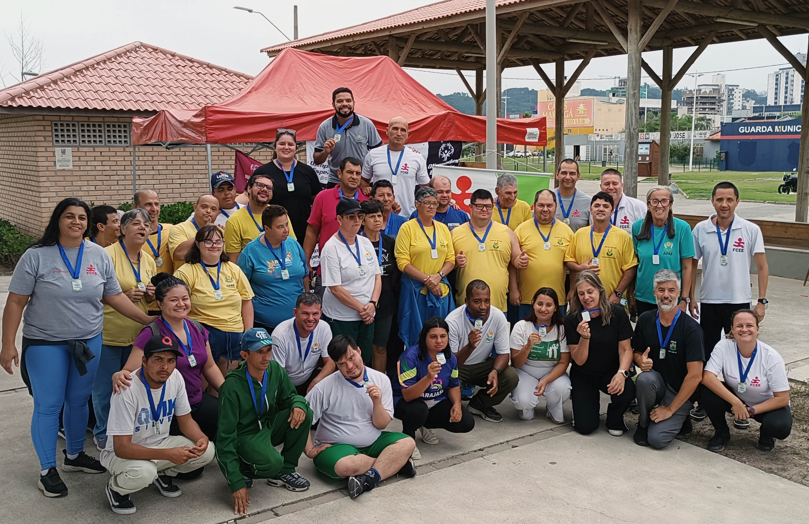 Participantes do Festival de Bocha Rafa da FCEE vinte pessoas posam para foto com medalhas em cancha de bocha ao ar livre