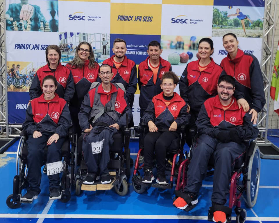Equipe de bocha da FCEE em Itajaí quatro cadeirantes e quatro pessoas em pé, com uniformes azul e vermelho